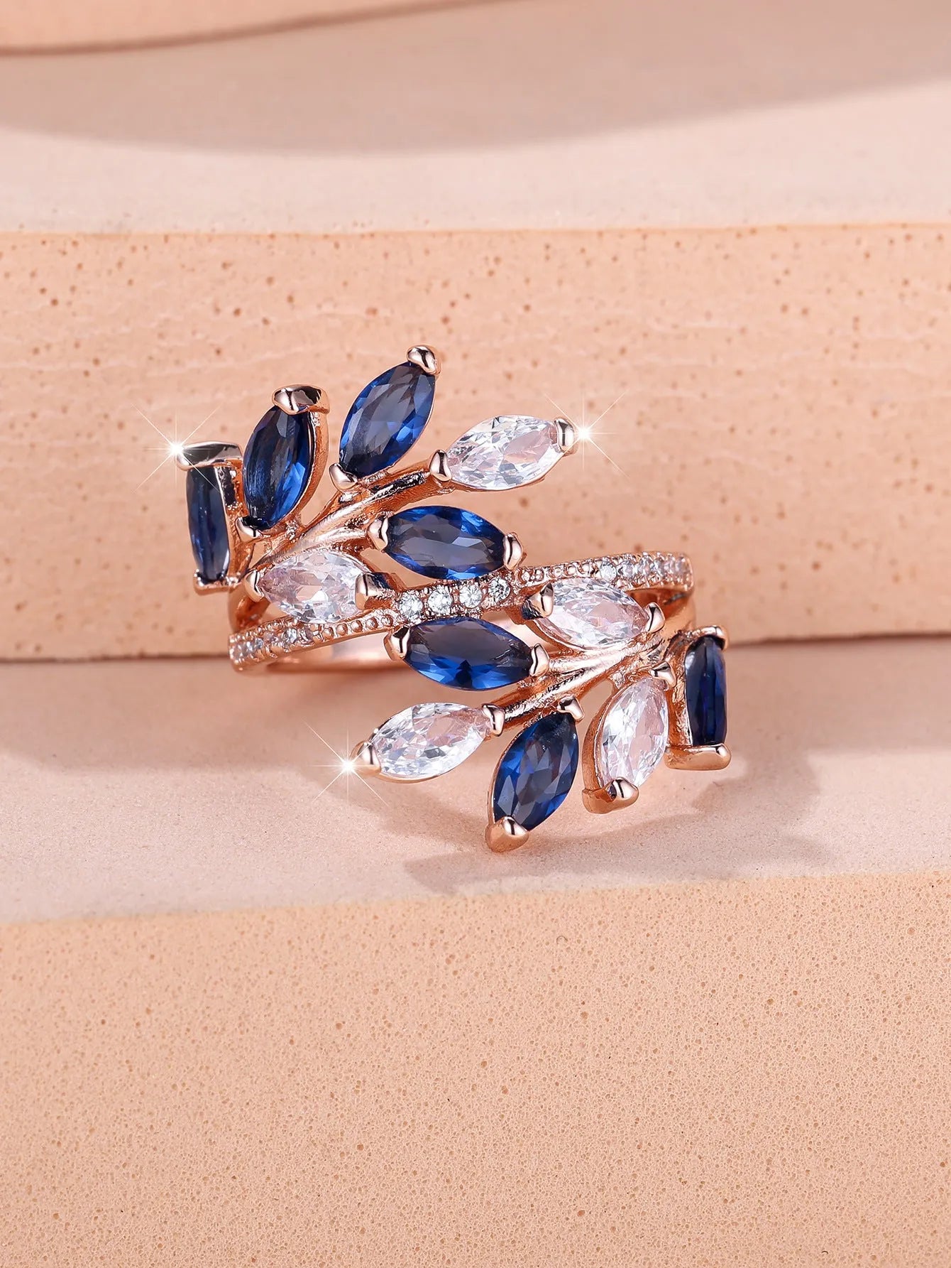 Adjustable copper leaf design ring with sparkling zircon stones on a model's finger.
