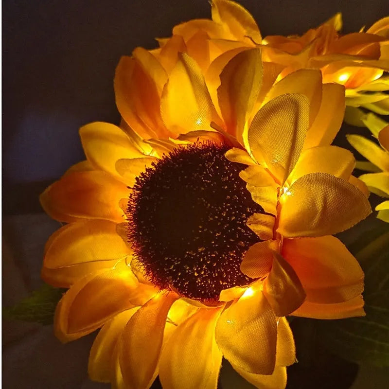 Rechargeable artificial sunflower LED table lamp with USB cable on wooden surface.
