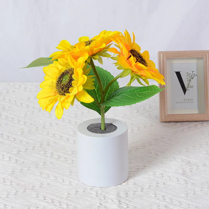 Rechargeable artificial sunflower LED table lamp with USB cable on wooden surface.