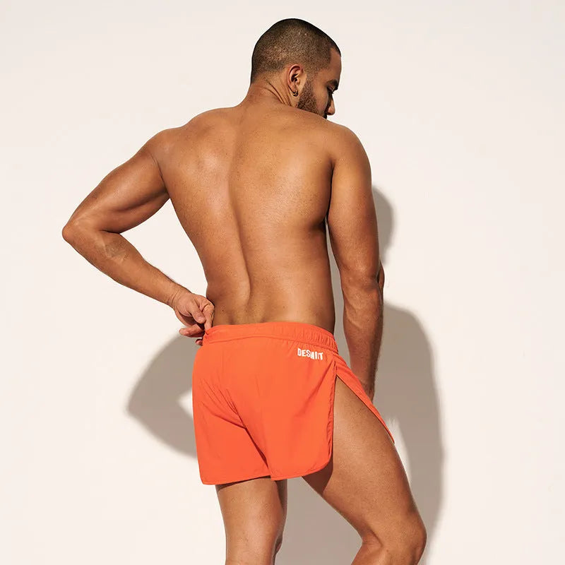 Men's loose polyester beach trousers in orange, fluorescent green, and black on a size chart