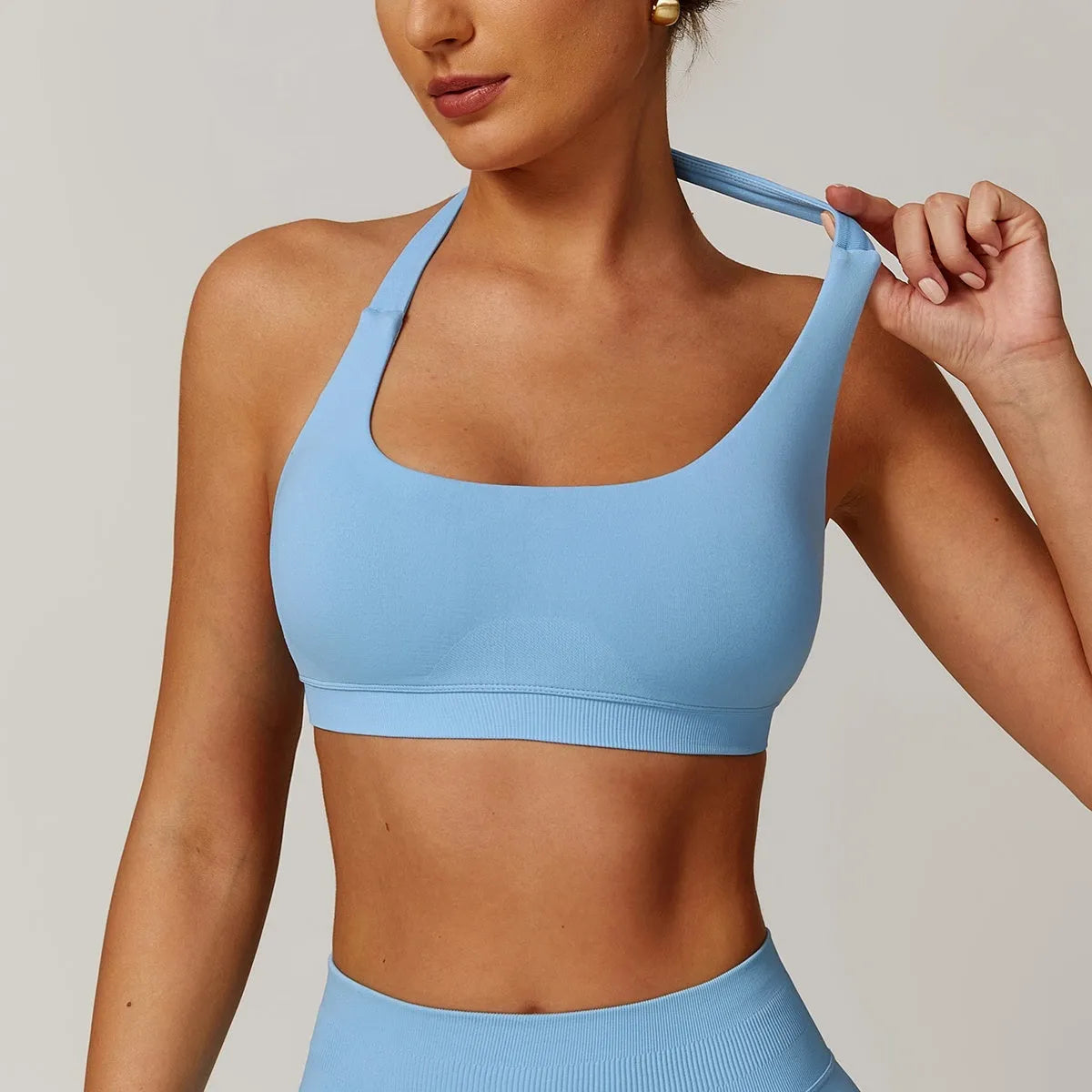 Women's black halter sports bra with hollow back and removable pads on a mannequin.