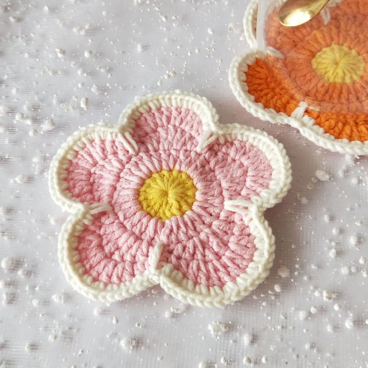 Five handmade woven flower placemats in blue, green, orange, pink and purple colours on a dining table