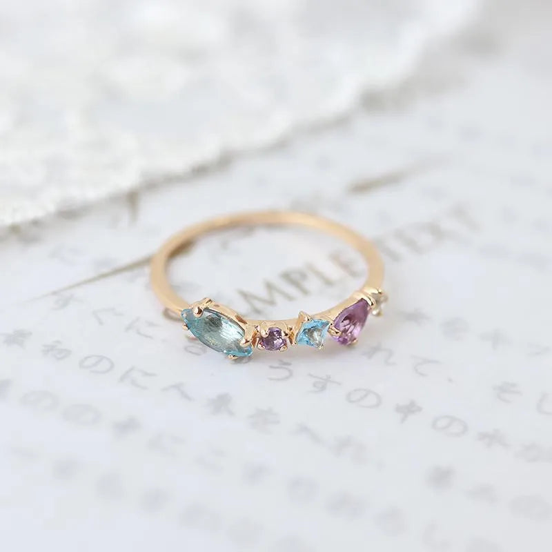 Gold-plated geometric ring with inlaid topaz and white amethyst stones on a white background