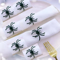 Set of six black alloy spider-shaped napkin rings for Halloween table decoration.