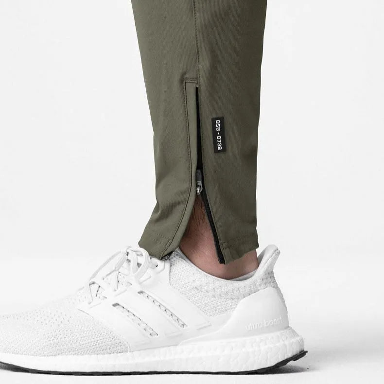 Man in loose grey fitness trousers with tied ankle cuffs, suitable for exercise.