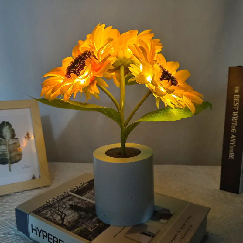 Rechargeable artificial sunflower LED table lamp with USB cable on wooden surface.