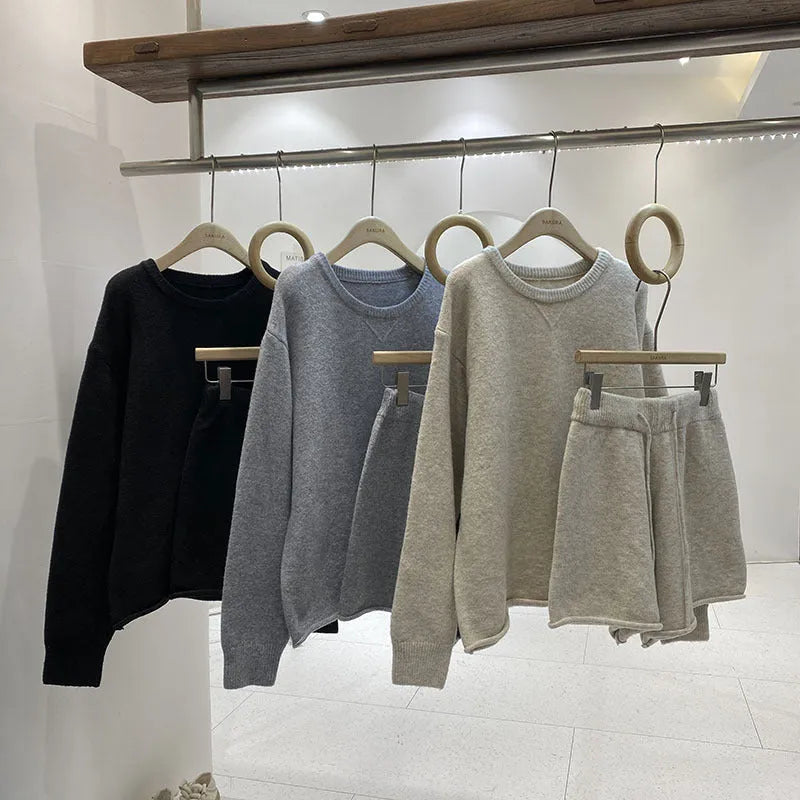 A woman's loose-fitting long sleeve knit sweater and matching wide-leg shorts set in a neutral colour.