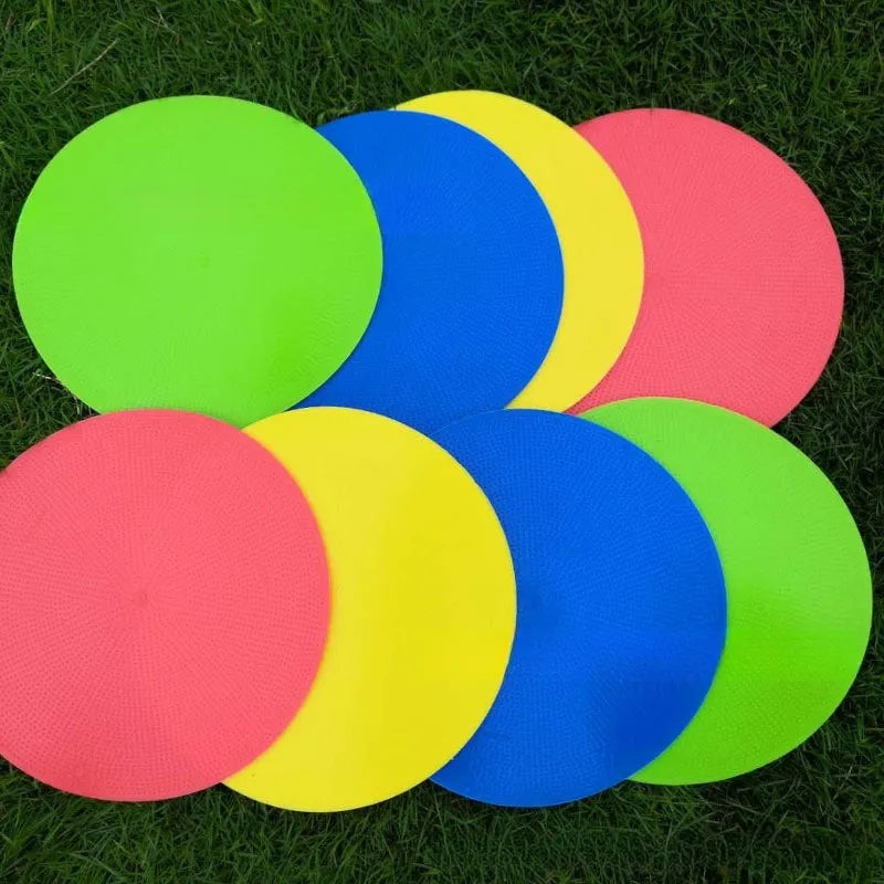 Soft TPE football training marker pad in assorted colours on grass, 23cm diameter.
