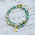 Close-up of an adjustable turquoise round bead bracelet with a three-ring pull-out clasp on a wrist.