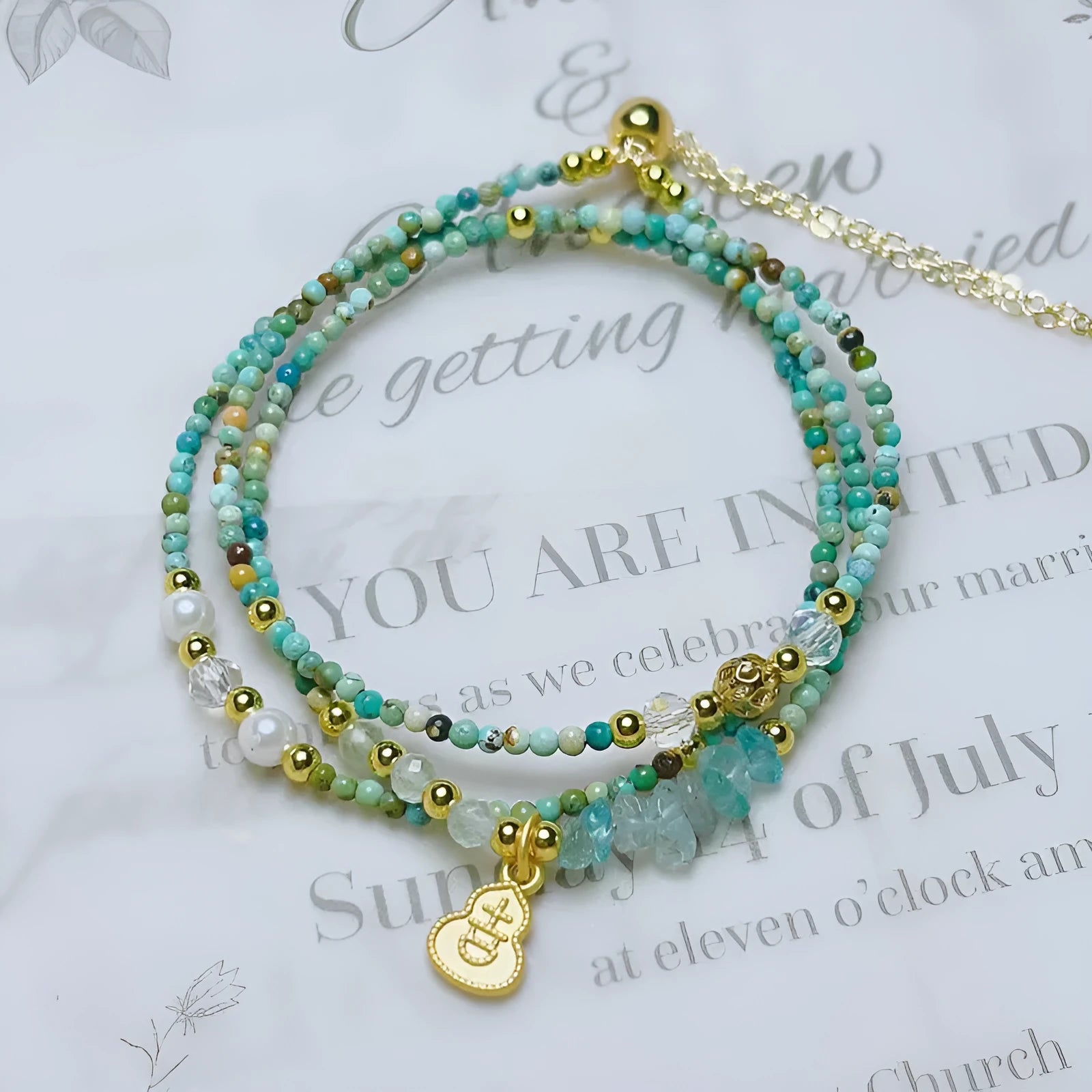 Close-up of an adjustable turquoise round bead bracelet with a three-ring pull-out clasp on a wrist.