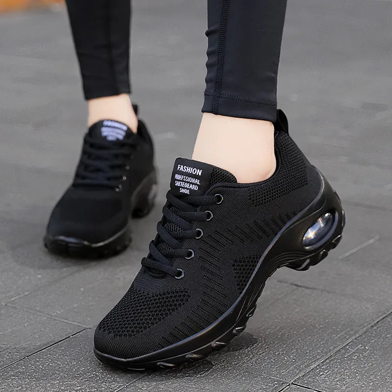 Women's black and red round toe mesh sneakers with front laces and a flat mid-heel.