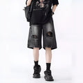 Man wearing loose-fit black denim shorts with ripped detailing and a washed vintage finish.