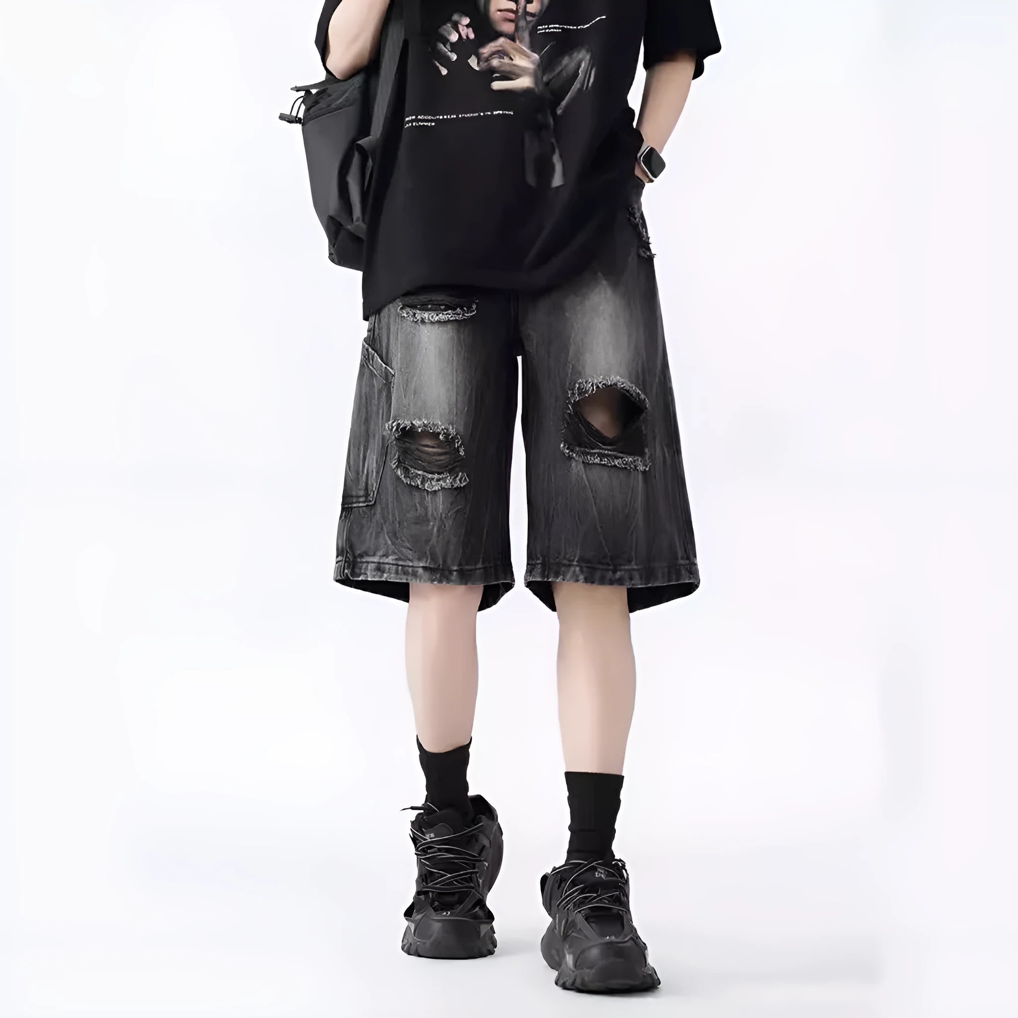 Man wearing loose-fit black denim shorts with ripped detailing and a washed vintage finish.