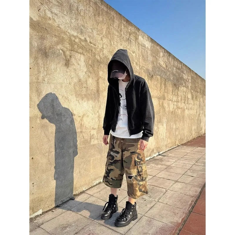Man wearing loose straight-cut camouflage jeans with patch ripped detailing and a cropped ankle length.