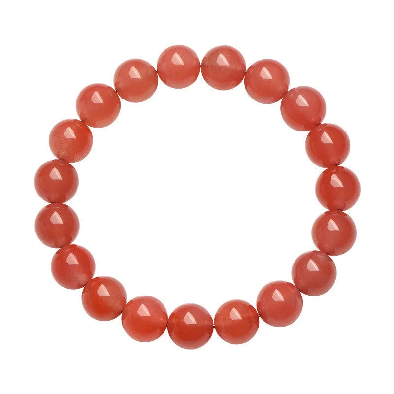 Scattered polished cherry red agate beads and elastic cord for a DIY bracelet next to an assembled single-strand bracelet.