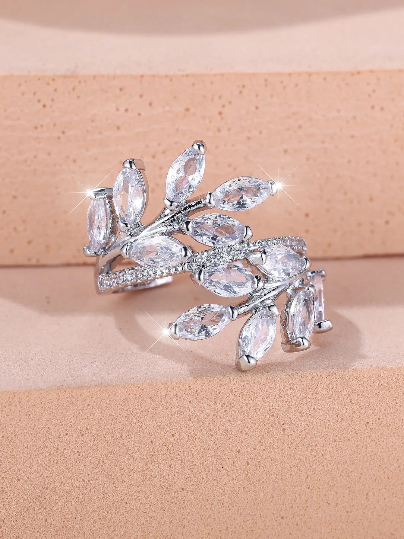 Adjustable copper leaf design ring with sparkling zircon stones on a model's finger.