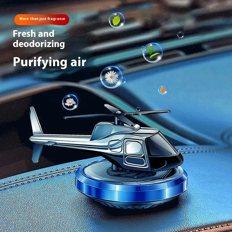 Silver metal solar helicopter car air freshener ornament rotating on a dashboard.