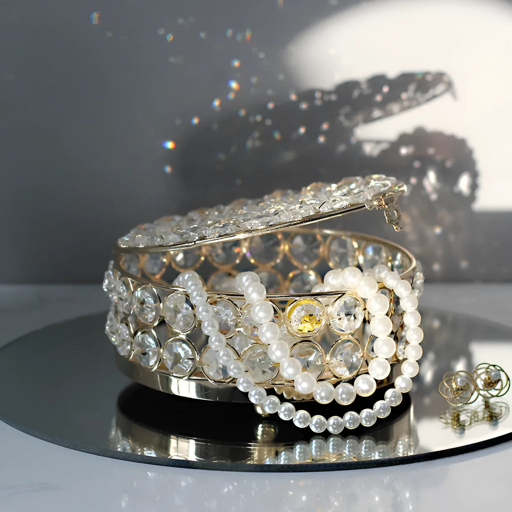 French gold metal jewelry box with a clear crystal glass lid and a lock, shown on a surface.