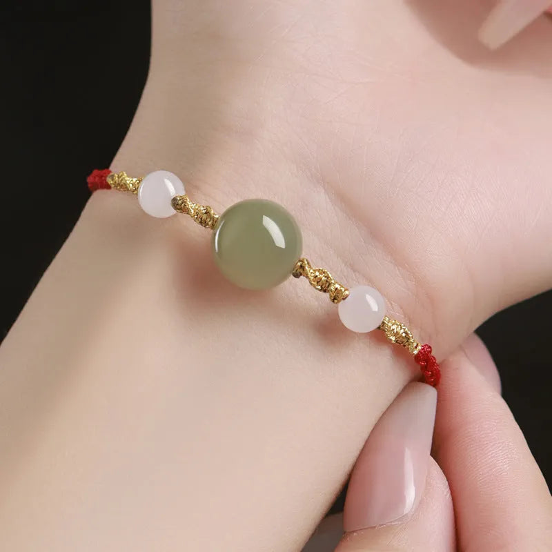 Handwoven Hetian jade lucky beads bracelet with red rope and cultural charm symbols in ethnic style