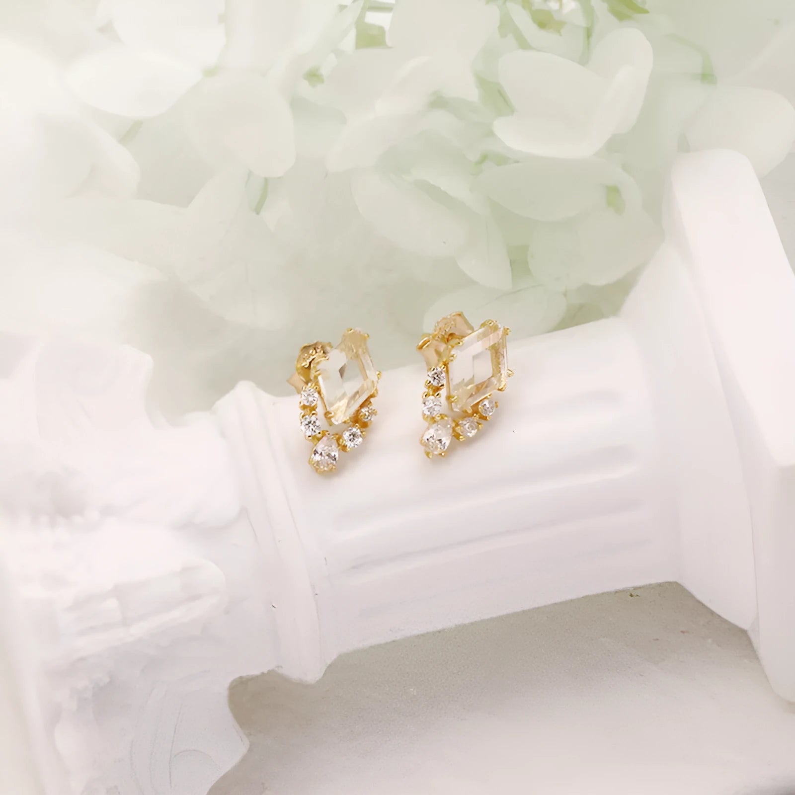 A pair of geometric shaped silver ear studs with sweet white crystal centres on a plain background.