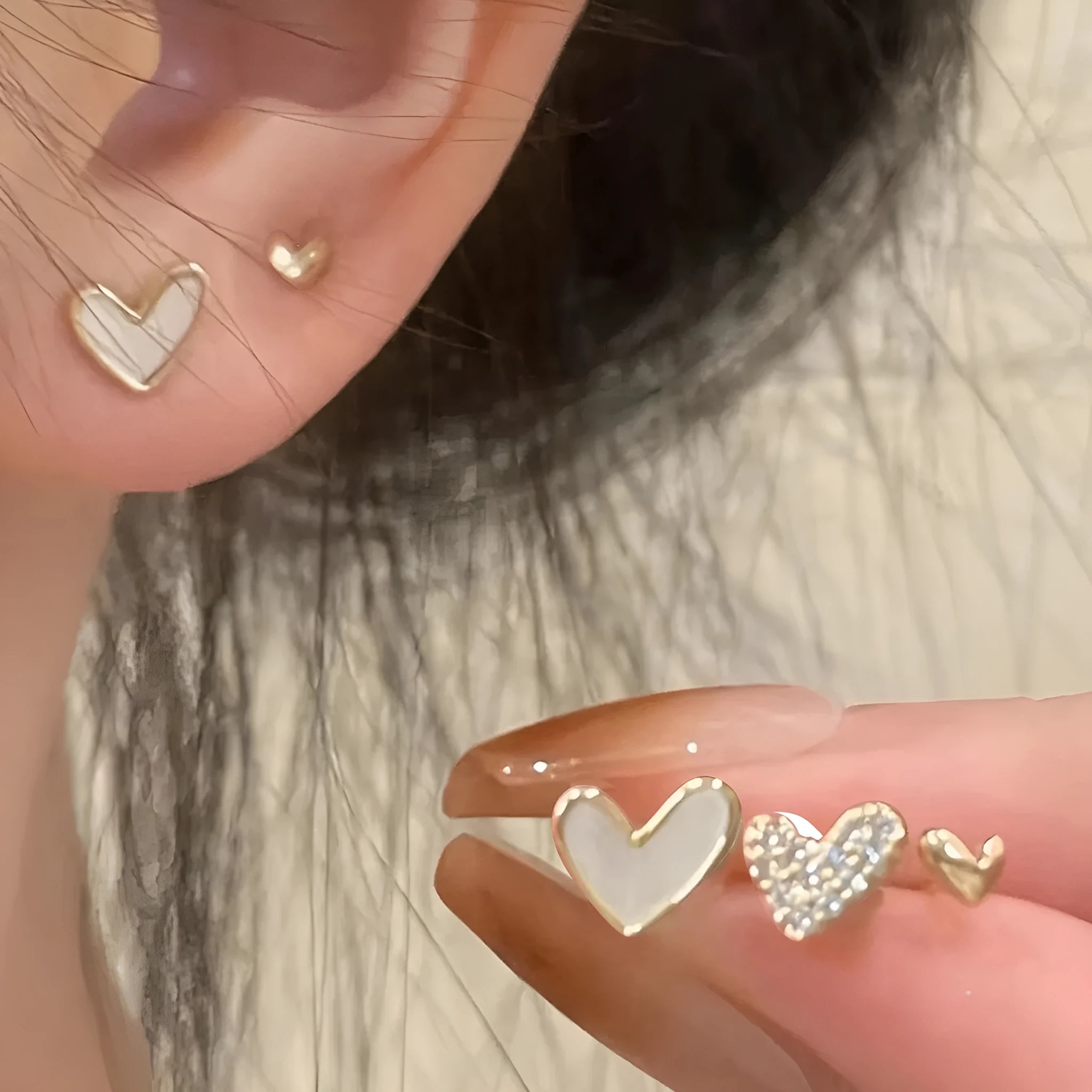 Three pairs of heart-shaped alloy earrings in gold, black, black and white, and pink electroplated colours