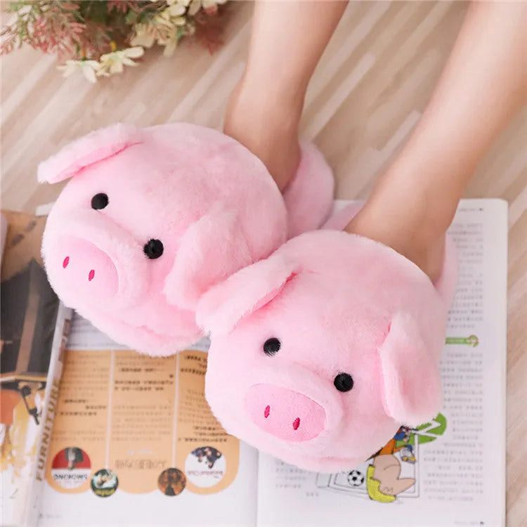 Pink pig-shaped plush floor slippers on a plain background.