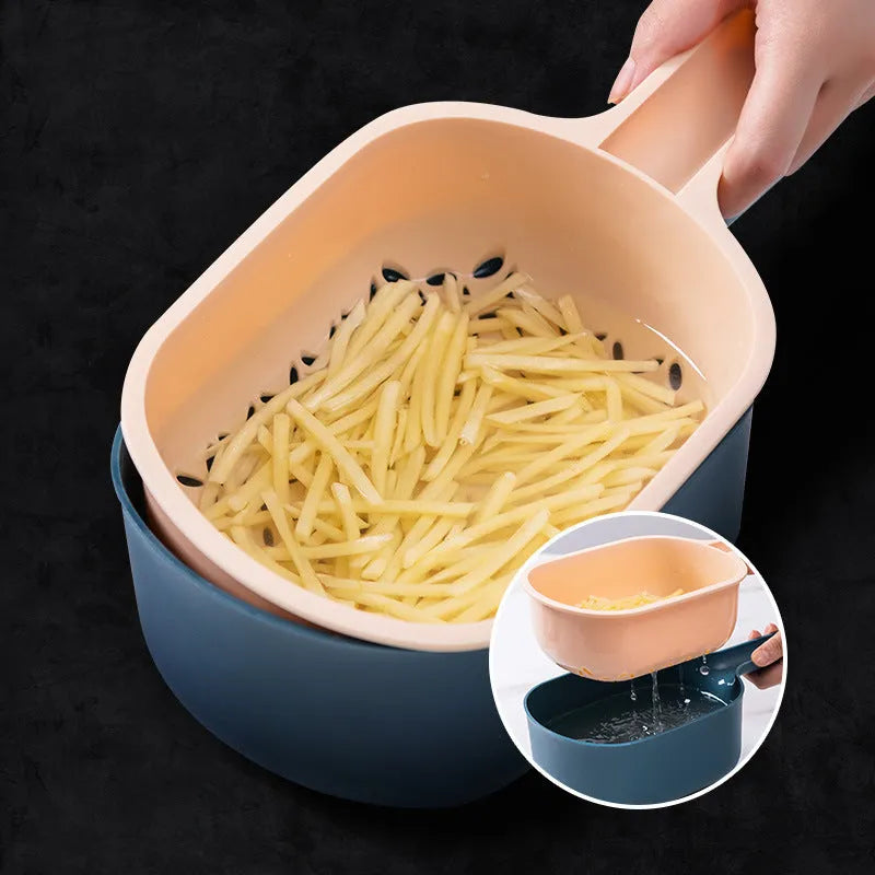 Dark blue vegetable cutter with four stainless steel blades, drain basket, and hand guard on a kitchen counter.