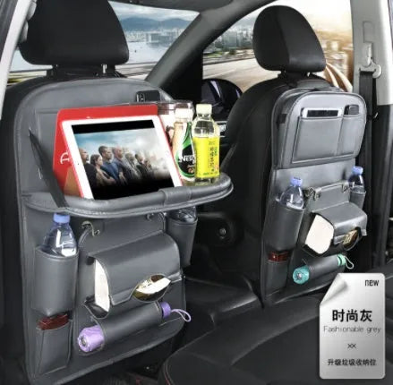 Black PU leather car seat back storage bag with multiple pockets hanging from a car headrest.