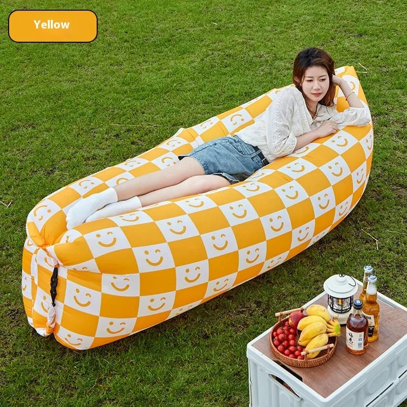 Yellow smiling face tip inflatable sofa inflated on green grass for camping