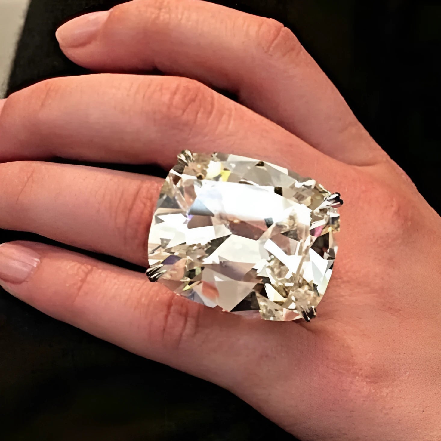 Simple geometric alloy ring with inlaid square diamond in white gold colour on a grey background.