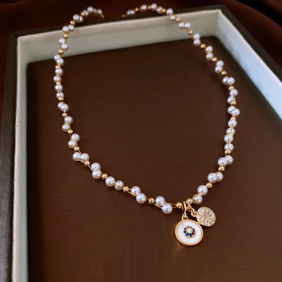 Gold electroplated necklace with round zircon-inlaid imitation pearl pendant on an adjustable clavicle chain.