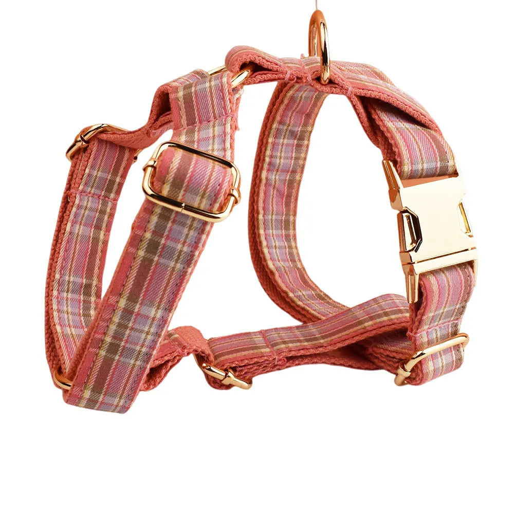 Plaid fabric dog collar, leash, bow, and vest four-piece accessory set on a white background.