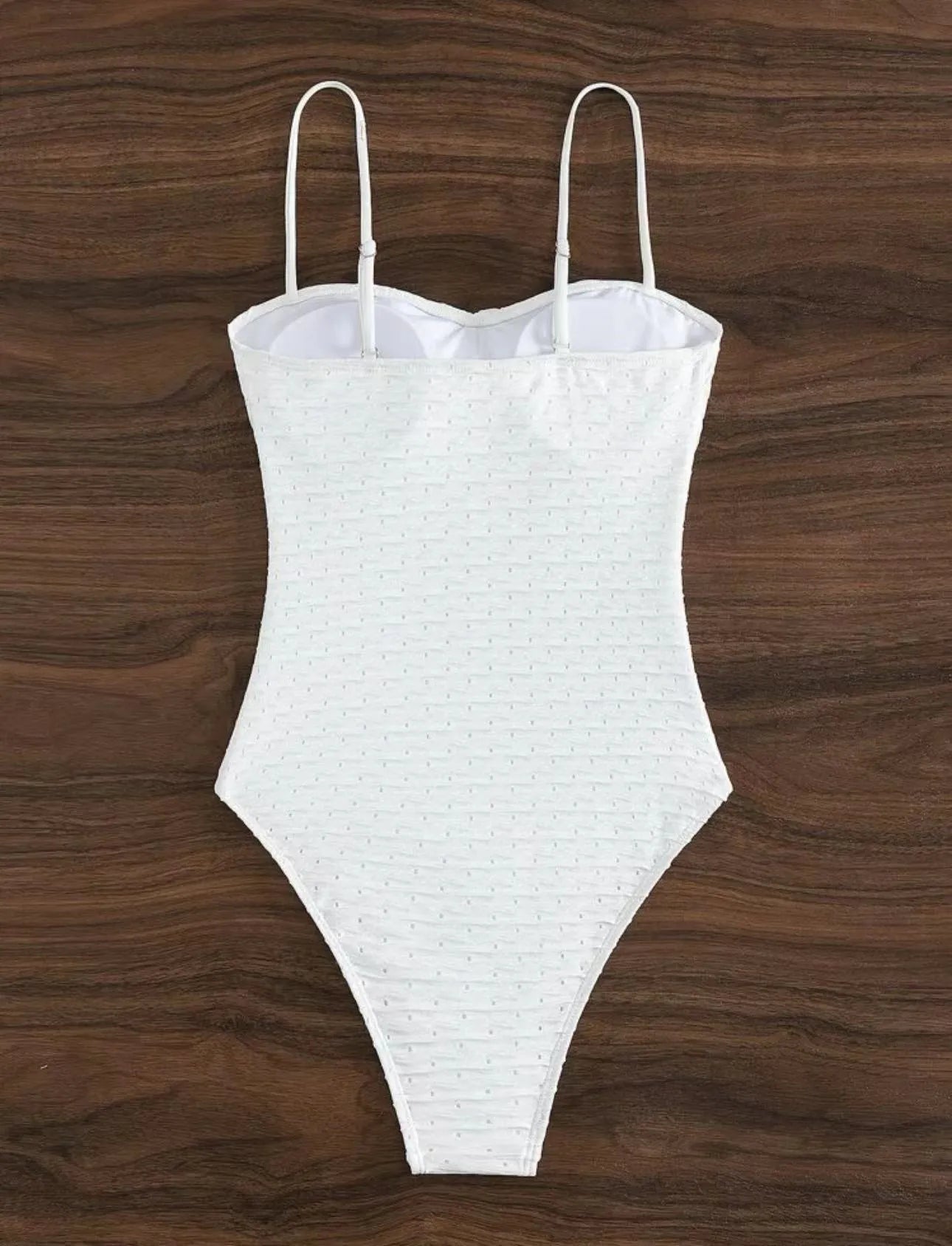 White one-piece swimsuit for women on a hanger, showing briefs style and sling detail.