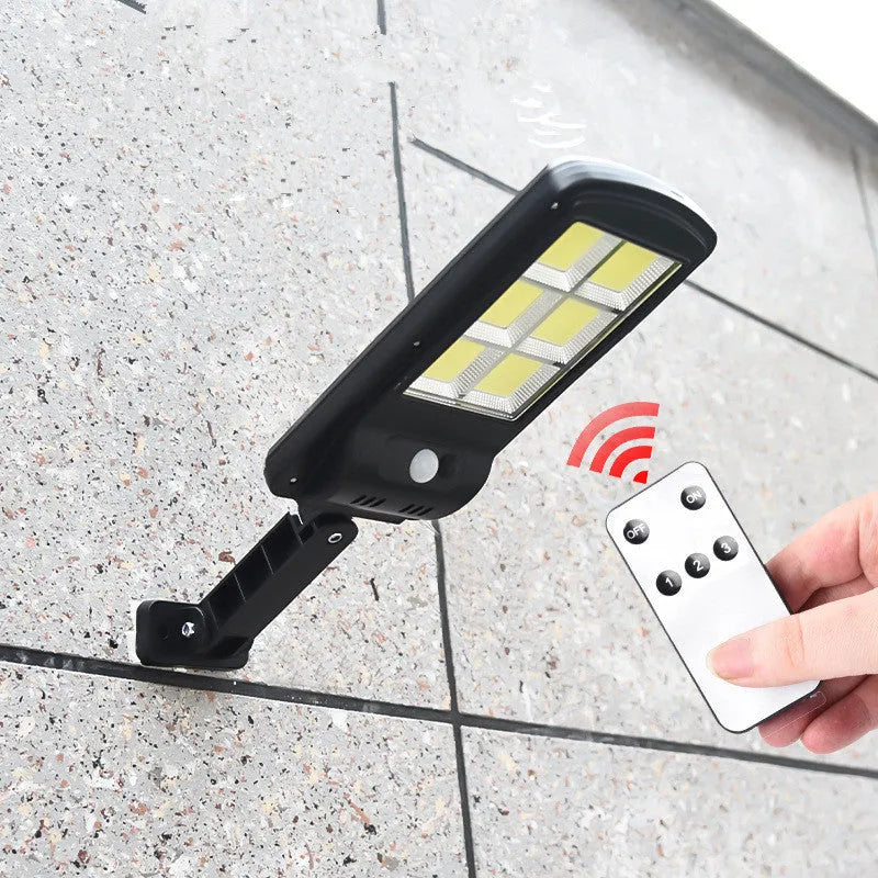 Black solar-powered outdoor motion sensor light mounted on a wall or fence post.