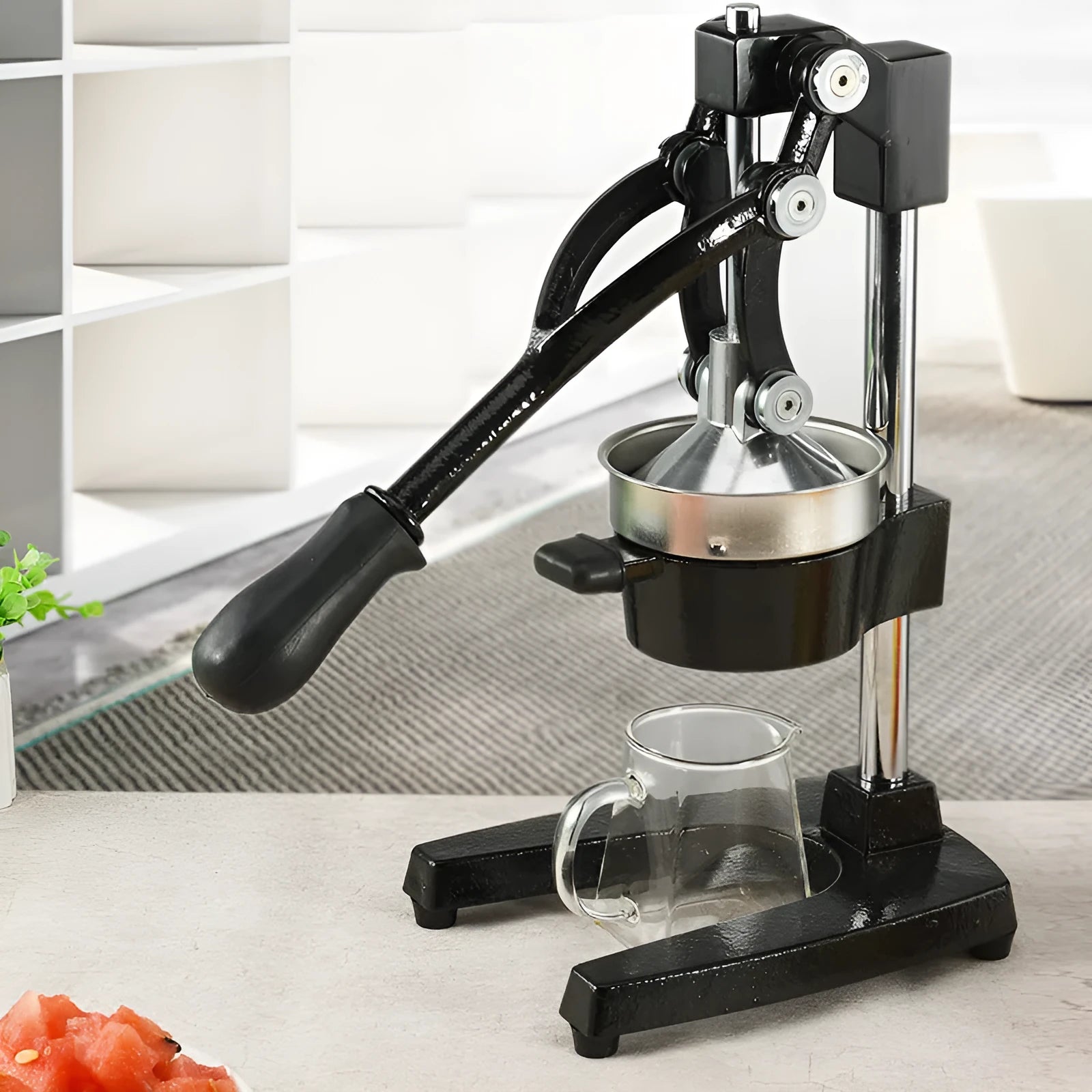 Black and white manual cast iron juicer with stainless steel funnel, 40 cm tall on kitchen counter.