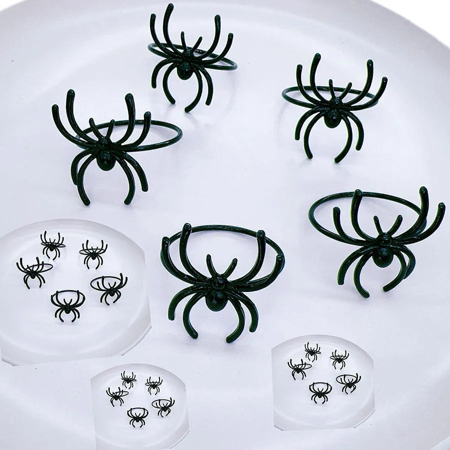 Set of six black alloy spider-shaped napkin rings for Halloween table decoration.