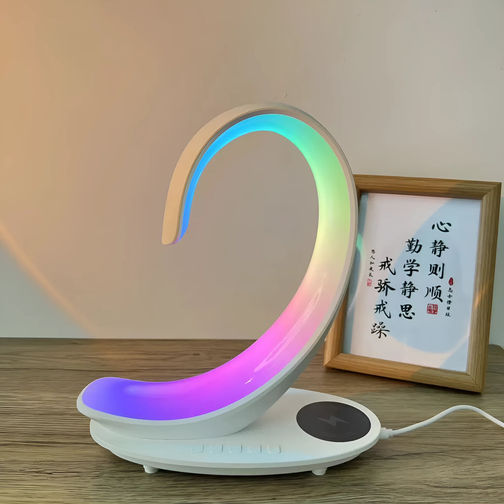 White swan sculpture desk lamp with integrated wireless phone charger and Bluetooth speaker emitting colourful light.