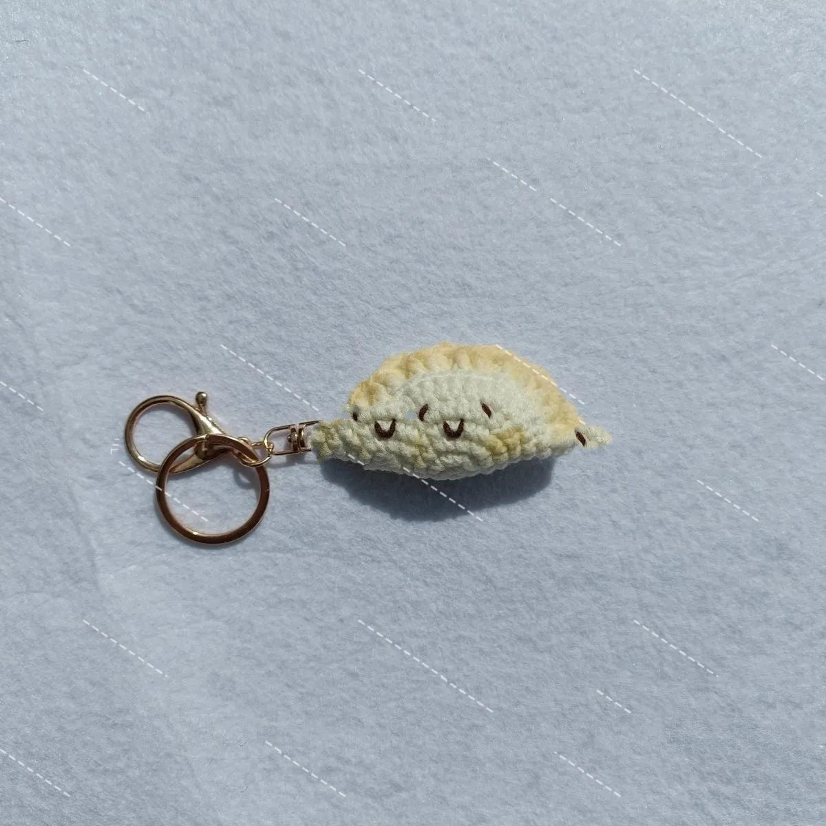 Handmade crochet dumpling pendant with keychain in plush material showing hand-stitched eye details