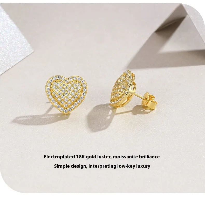 A pair of golden heart-shaped moissanite stud earrings on an S925 silver post.