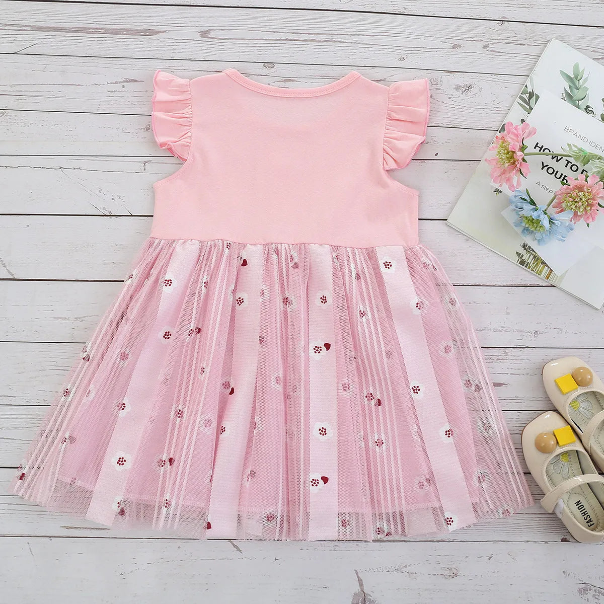 Pink cotton girls princess dress with cartoon rabbit print and mesh overlay on plain background
