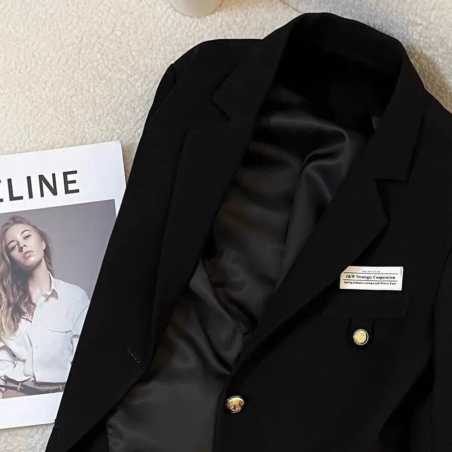 Women's black short suit coat with loose fit and pocket detail on hanger