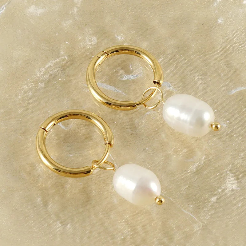 Gold geometric drop earrings with a freshwater pearl detail on a stainless steel setting.