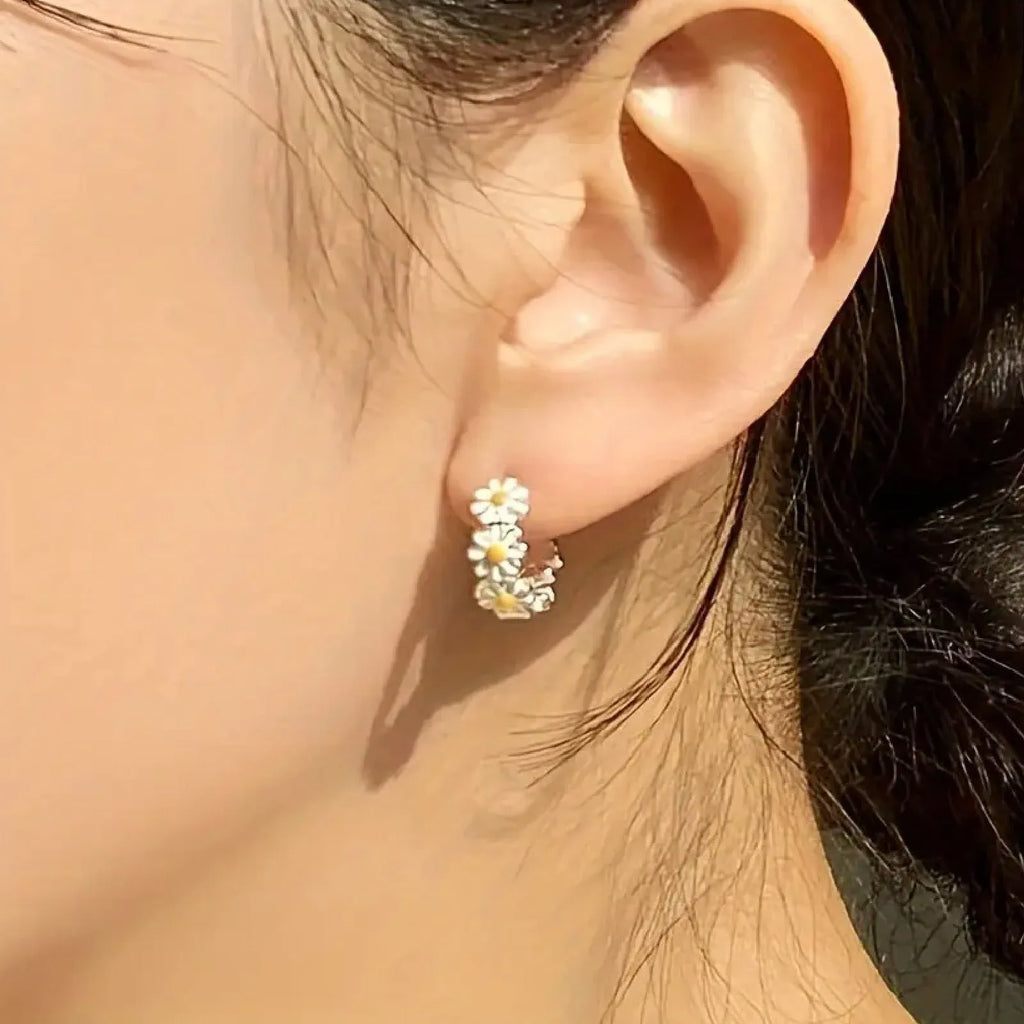 White daisy flower copper earrings with platinum gem accents on display