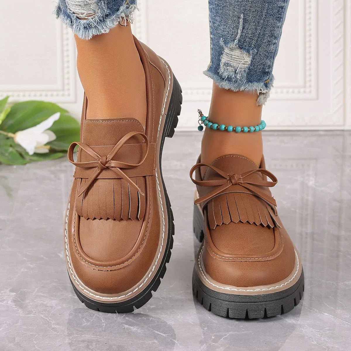 Black plus size women's loafers with a front bowknot and tassel on a chunky flat rubber sole.