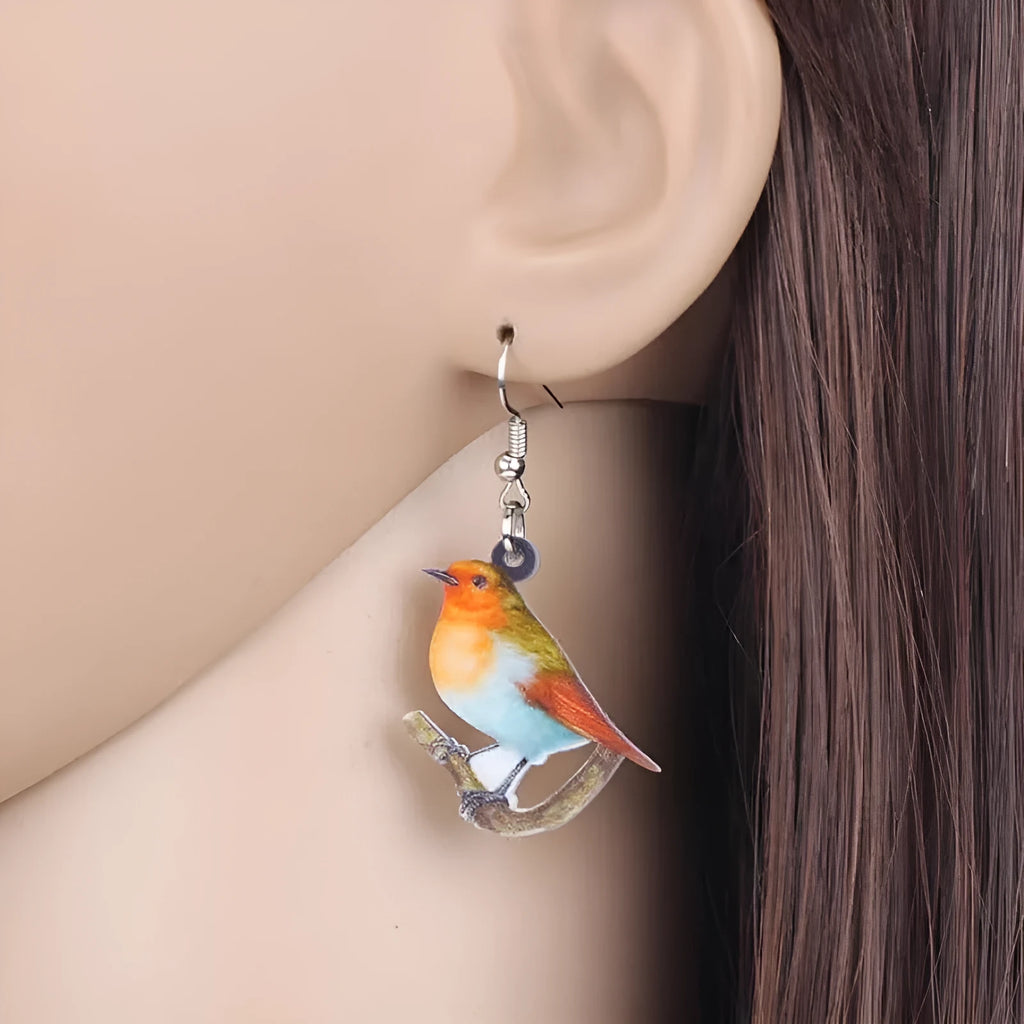 A pair of blue titmouse pendant earrings made from acrylic with printed snake and geometric designs.