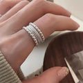 Copper alloy geometric ring with woven twisted design and adjustable opening.
