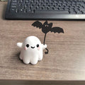 Small white resin statue of a ghost walking a spectral dog, a Halloween decoration.