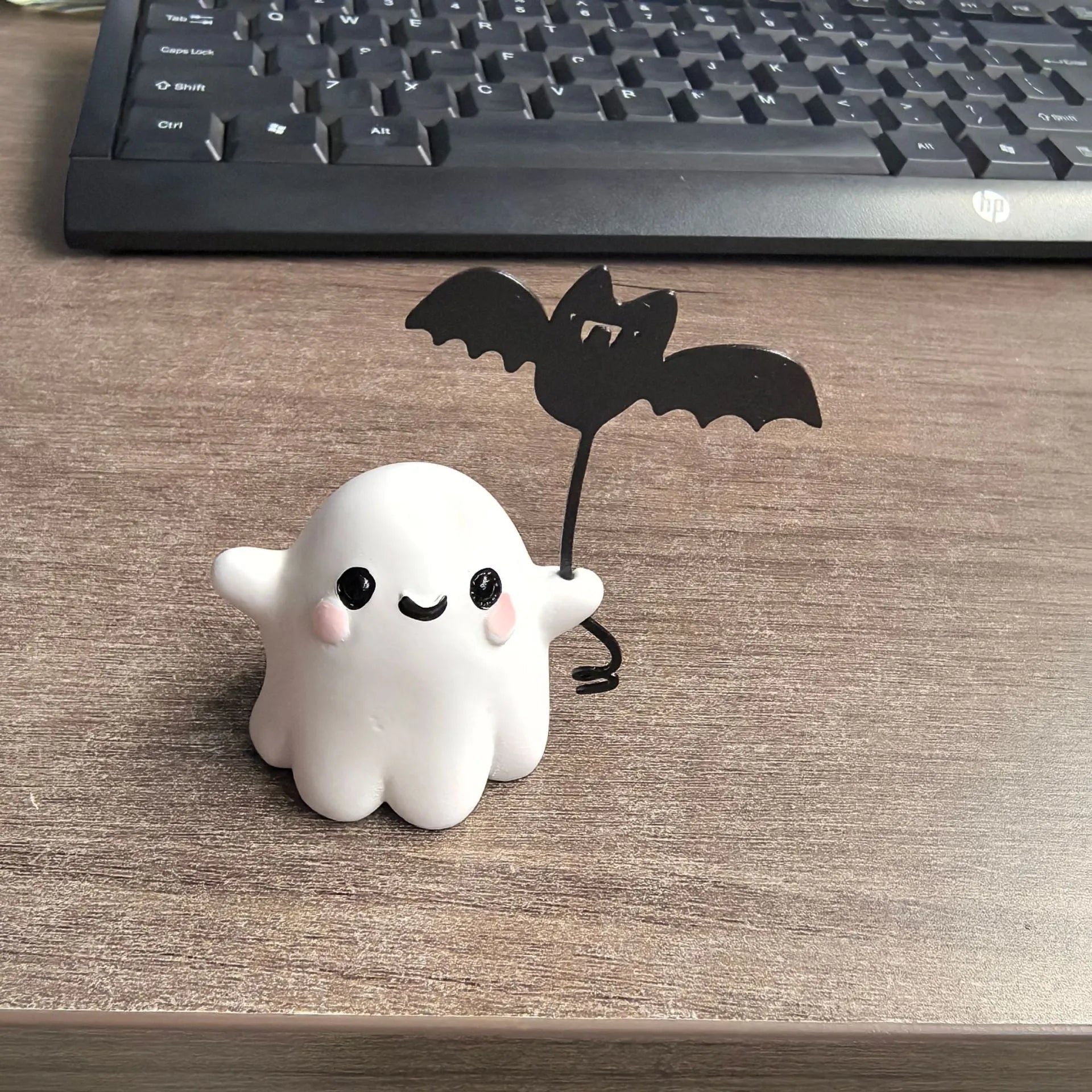 Small white resin statue of a ghost walking a spectral dog, a Halloween decoration.