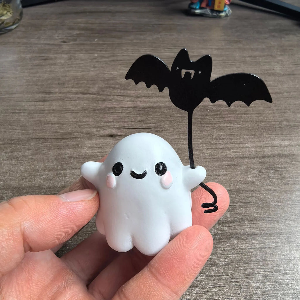 Small white resin statue of a ghost walking a spectral dog, a Halloween decoration.