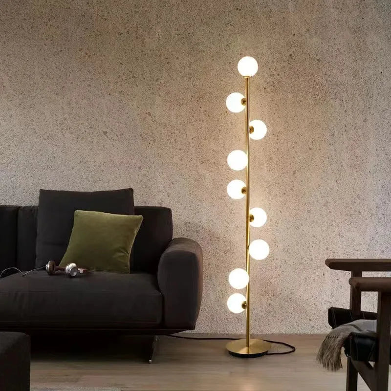 A tall modern minimalist floor lamp with a glass shade, wrought iron frame, and a grey marble base.